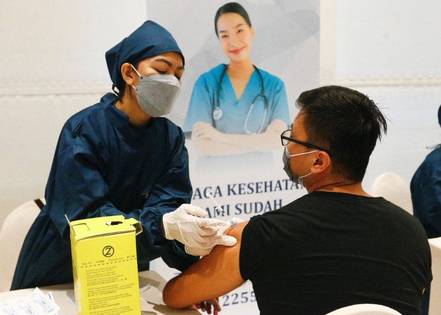 A healthcare worker inoculates a man with China's Sinovac Biotech vaccine for the coronavirus disease (Covid-19) during the mass vaccination program at a shopping mall in Jakarta, Indonesia, 1 April 2021. (Ajeng Dinar Ulfiana/Reuters)