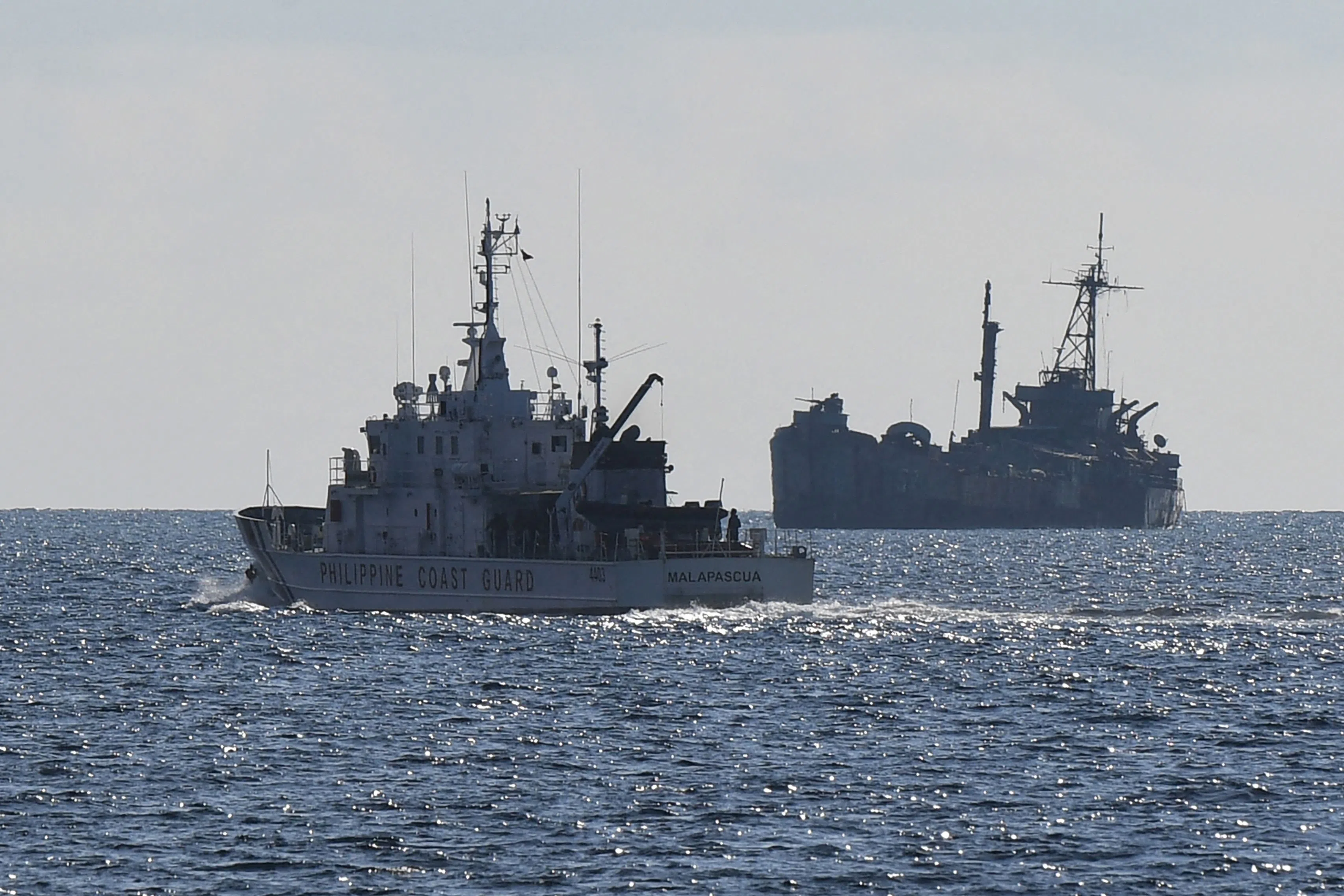 This file photo taken on 23 April 2023 shows Philippine coast guard vessel BRP Malapascua (left) patrolling near the grounded navy ship BRP Sierra Madre where Philippine marines are stationed to assert Manila’s territorial claims at Second Thomas Shoal in the Spratly Islands in the disputed South China Sea. (Ted Aljibe/AFP)