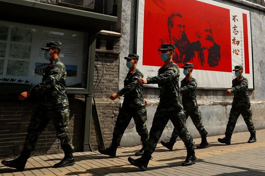 Chinese servicemen walk past portraits of German philosophers Karl Marx and Friedrich Engels and patrol a street near the Great Hall of the People on the opening day of the National People's Congress (NPC) in Beijing, China, on 22 May 2020. (Thomas Peter/Reuters)