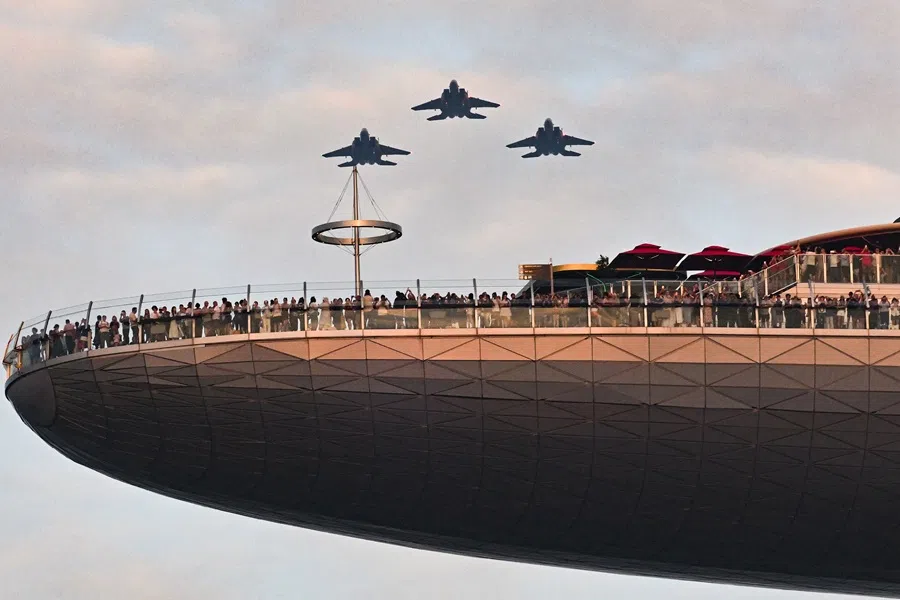 People at the Marina Bay Sands SkyPark watching F-15SG fighter jets fly overhead during the multi-axis fly-past at the National Day Parade 2025 National Education Show 2 on 5 July 2025. (SPH Media)