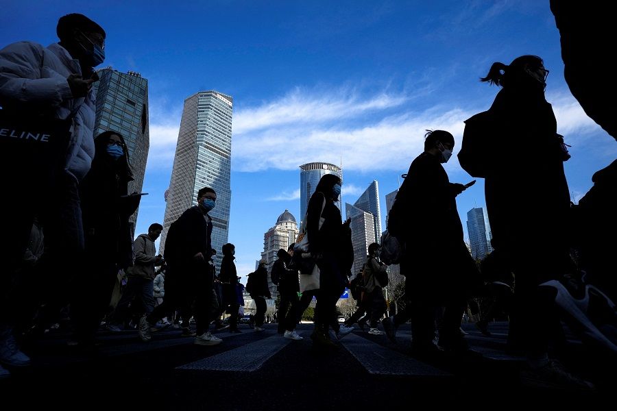 People cross a street near office towers in the Lujiazui financial district in Shanghai, China, 28 February 2023. (Aly Song/Reuters)