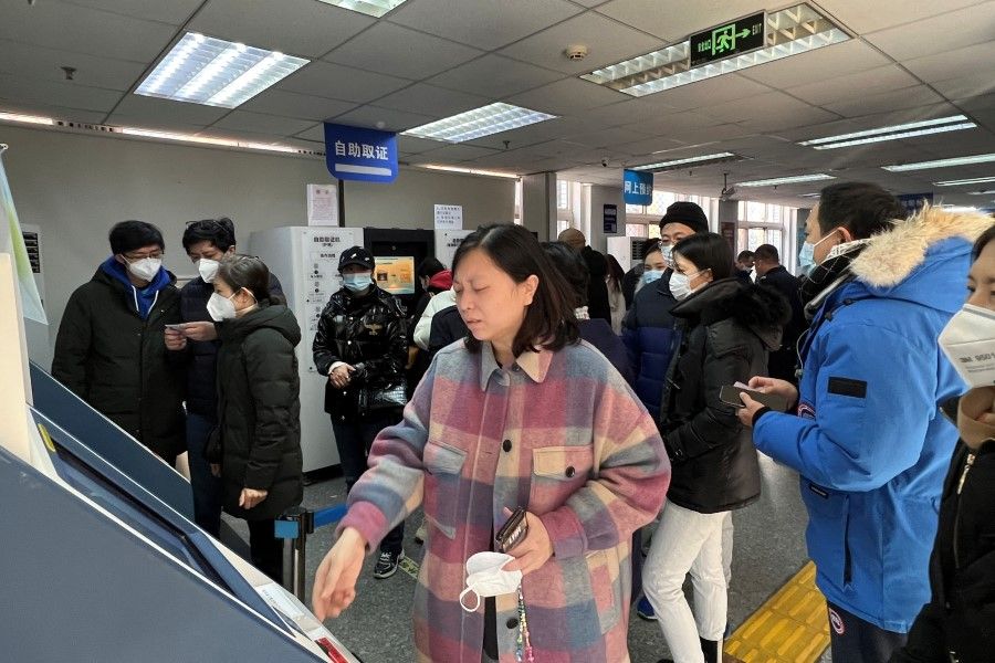 People process affairs at a government office for entry and exit matters which provides services including making or renewing passports or permits to go to Hong Kong, Macau and Taiwan, after China reopened borders, in Beijing, China, 9 January 2023. (Yew Lun Tian/Reuters)