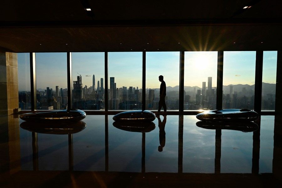A man walks along an observation area with a view of the Shenzhen skyline during sunset in Shenzhen, in China's southern Guangdong province on 10 July 2022. (Jade Gao/AFP)