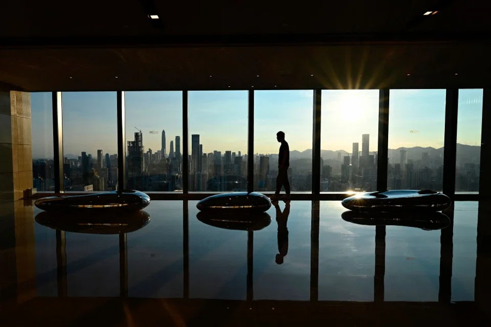 A man walks along an observation area with a view of the Shenzhen skyline during sunset in Shenzhen, in China's southern Guangdong province on 10 July 2022. (Jade Gao/AFP)