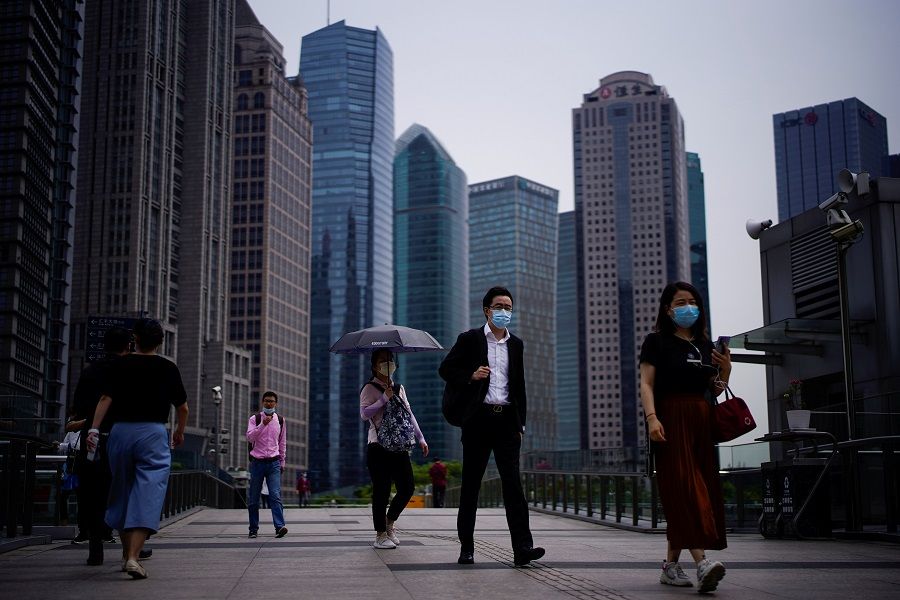 People wearing protective face masks walk past office buildings in Lujiazui financial district in Pudong, Shanghai, on 4 June 2020. (Aly Song/Reuters)