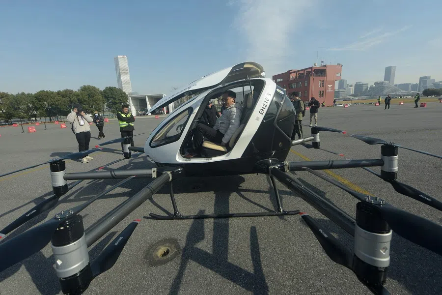 This photo taken on 16 January 2025 shows a man (centre) sitting in an EH216-S, a two passenger electric vertical take-off and landing (eVTOL) multicopter production model made by Guangzhou EHang Intelligent Technology Co. Ltd. (EHang), during its first public flight in Shanghai, at Longhua Heliport, China. (AFP)