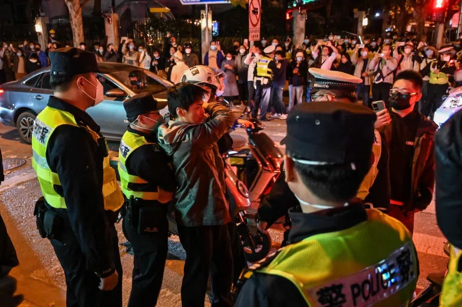 Police officers confront a man as they block Wulumuqi street, named for Urumqi in Mandarin, in Shanghai on 27 November 2022, in the area where protests against China's zero-Covid policy took place the night before following a deadly fire in Urumqi, the capital of the Xinjiang region. (Hector Retamal/AFP)
