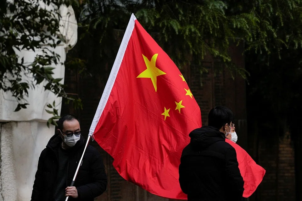 People wearing face masks pose for photos with a Chinese national flag at a park in Shanghai, China, 12 December 2022. (Aly Song/Reuters)