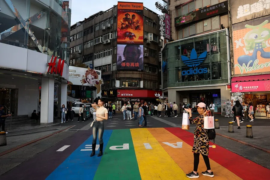 People take photos at a shopping district in Taipei, Taiwan, on 19 February 2024. (Ann Wang/Reuters)