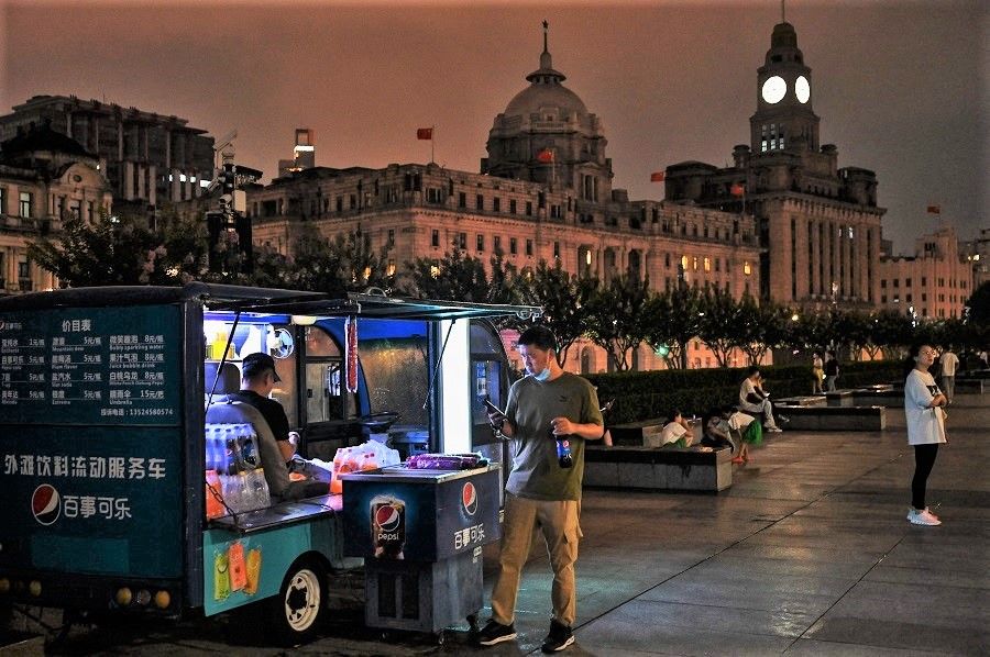 A man buys a soft drink from a vendor in the Bund promenade along the Huangpu River in Shanghai, China, on 23 August 2022. (Hector Retamal/AFP)