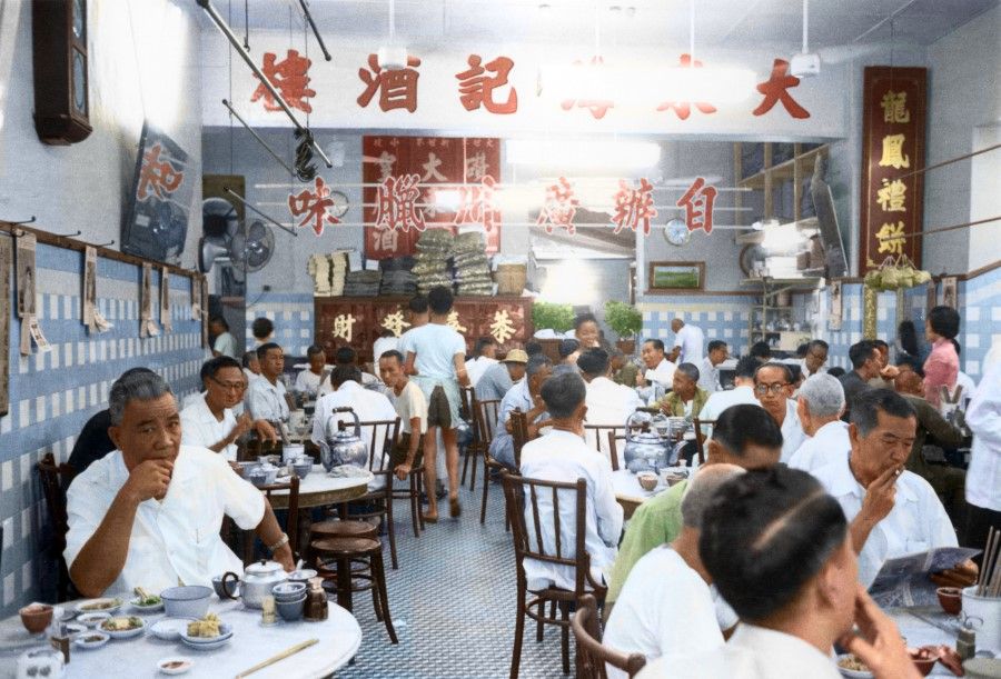 A crowded restaurant in the 1960s. The sign in Chinese advertises homemade Cantonese meats, indicating that this is a Cantonese restaurant. Cantonese-style "yum cha" or "drink tea" (usually with dim sum) is a popular breakfast in Singapore.