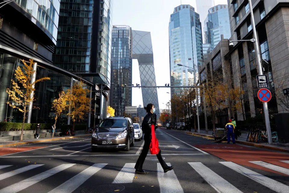 A woman walks across the street during morning rush hour, following the outbreak of the coronavirus disease (COVID-19), in the Central Business District (CBD) in Chaoyang District, Beijing, China, 21 November 2022. (Tingshu Wang/Reuters)