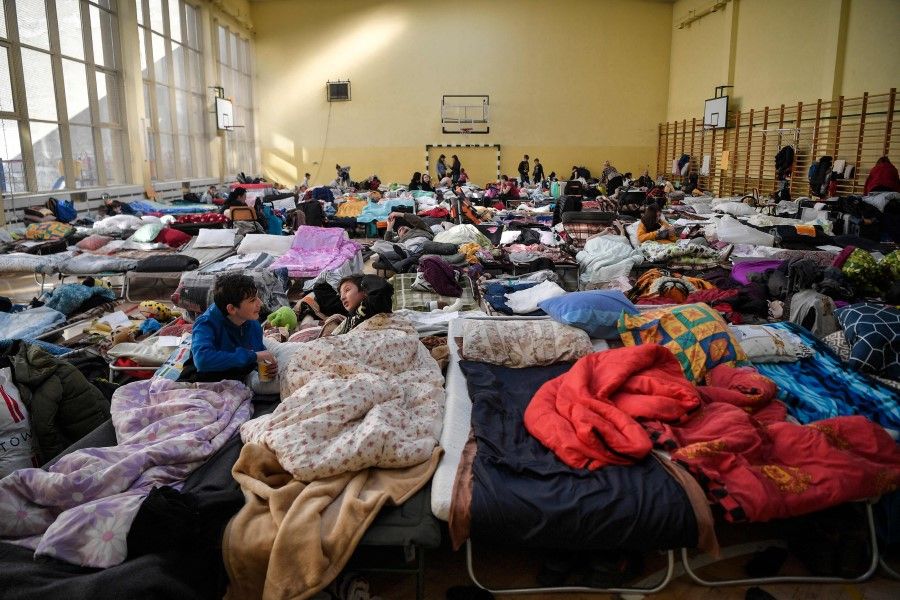 People rest in a temporary shelter for Ukrainian refugees in a school in Przemysl, near the Ukraine-Poland border on 14 March 2022. (Louisa Gouliamaki/AFP)