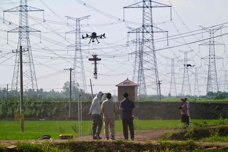 Workers fly a drone to conduct live measurements on power lines in Huai’an, in China’s eastern Jiangsu province on 17 July 2025. (AFP)