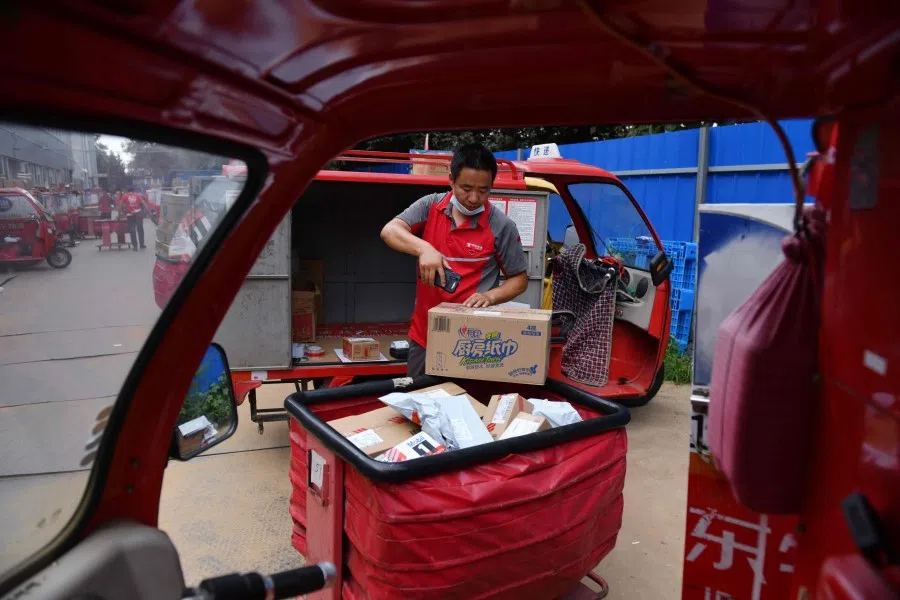 A worker scans a package before loading it into his delivery cart at a JD.com distribution center in Beijing on 16 July 2020. (Greg Baker/AFP)