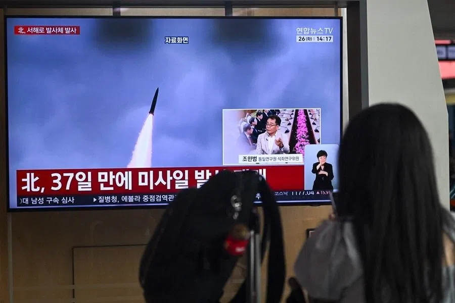 A woman watches a television screen showing a news broadcast with file footage of a North Korean missile test, at a train station in Seoul on 26 May 2026.