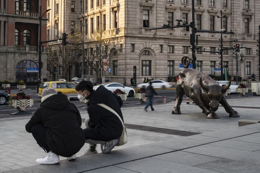 Two men kneel near the Bund Bull statue in Shanghai, China, on 21 December 2020.(Qilai Shen/Bloomberg)
