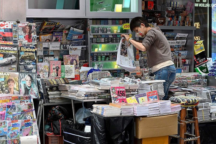 This photo taken on 6 January 2022 shows a vendor sorting newspapers at a newsstand in Hong Kong. (Peter Parks/AFP)