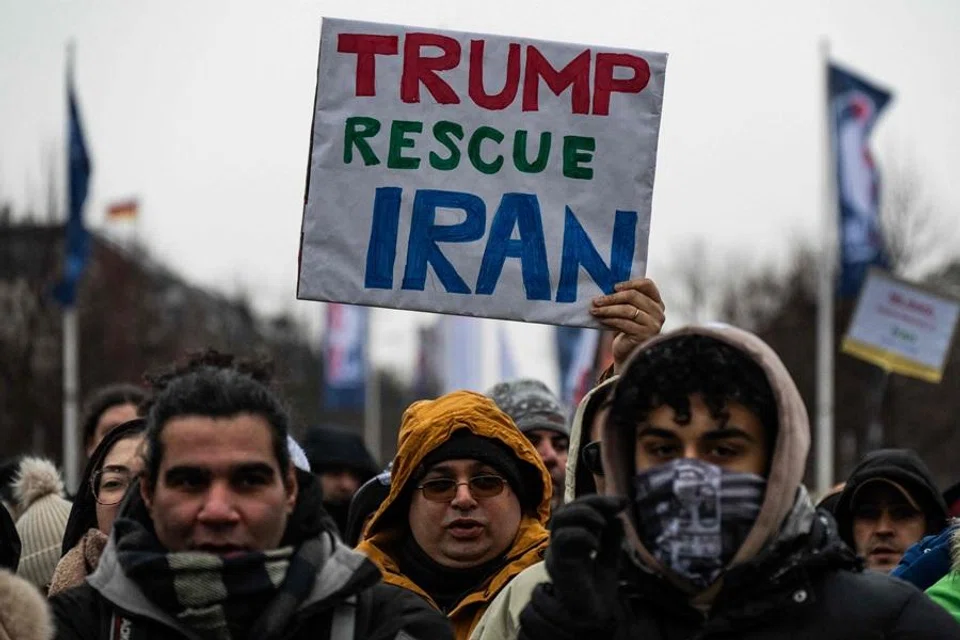 A demonstrator displays a placard calling for the US president to intervene in Iran during an anti-Iranian-government protest in Berlin, Germany, on 12 January 2026. (John MacDougall/AFP)