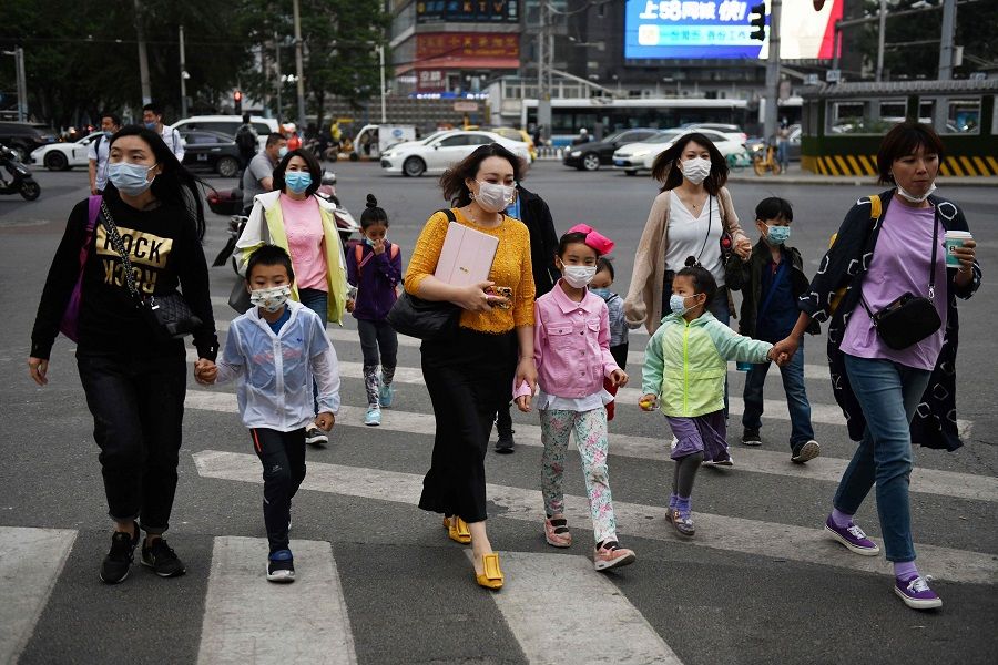 A group of women and children wear face masks as a precaution against the Covid-19 coronavirus as they cross a road in Beijing on 15 May 2020. (Greg Baker/AFP)