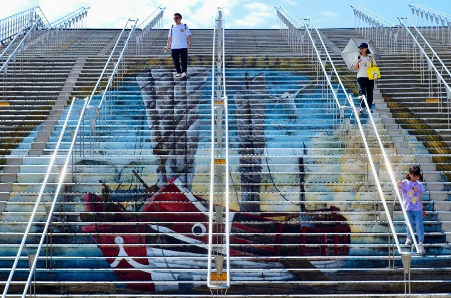 Visitors climb down stairs decorated with a 3-D painting at the Shihsanhang Museum of Archaeology at the Bali District of New Taipei City on 8 June 2024.  (Sam Yeh/AFP)