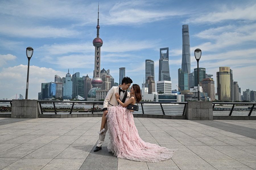 A couple poses during a pre-wedding photo session on the promenade on the Bund along the Huangpu River in Shanghai, China, on 24 September 2021. (Hector Retamal/AFP)