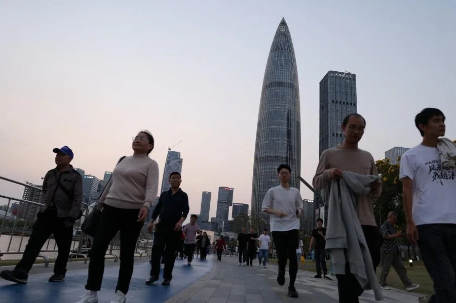 People walk in a park at dusk with the central business district in the background in Shenzhen, Guangdong province, China, on 18 March 2026. (Tingshu Wang/Reuters)