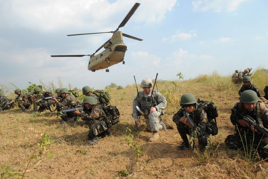 This file photo taken on 20 April 2015 shows Philippine soldiers and a US Army soldier from the 2nd Stryker Brigade Combat unit of the 5th Infantry Division based in Hawaii taking their positions after disembarking from a C-47 Chinook helicopter during an air assault exercise inside the military training camp at Fort Magsaysay in Nueva Ecija province. (Ted Aljibe/AFP)