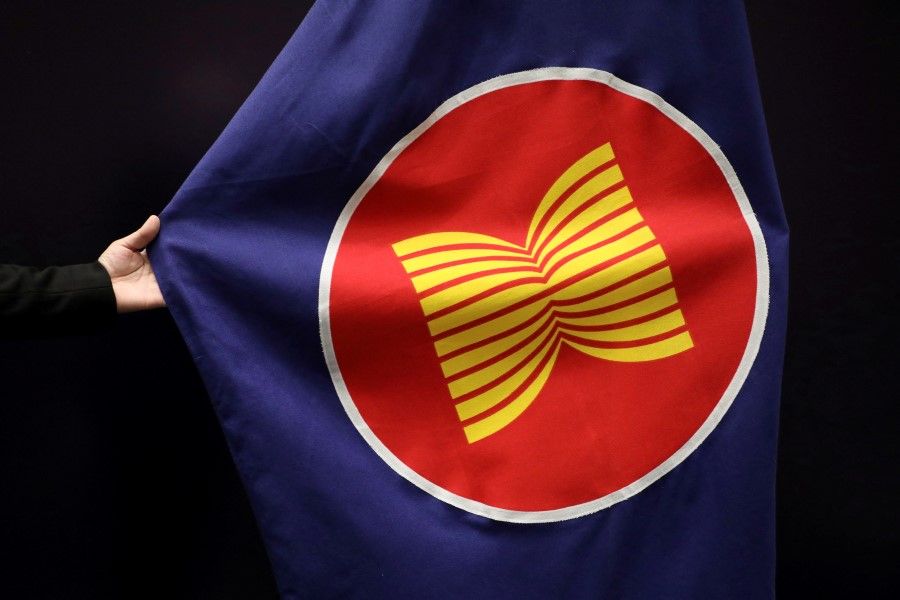 A worker adjusts an ASEAN flag at a meeting hall in Kuala Lumpur, Malaysia, 28 October 2021. (Lim Huey Teng/Reuters)