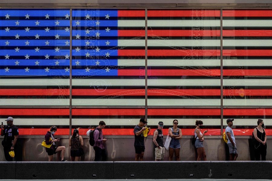 People queue to board a tourist bus before a display showing a US flag in Times Square in New York City, US on 30 July 2021. (Ed Jones/AFP)