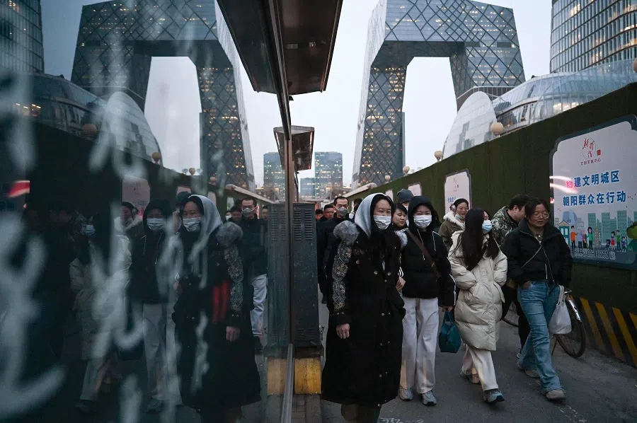 People walk on a sidewalk in the central business district in Beijing, China, on 28 February 2024. (Greg Baker/AFP)