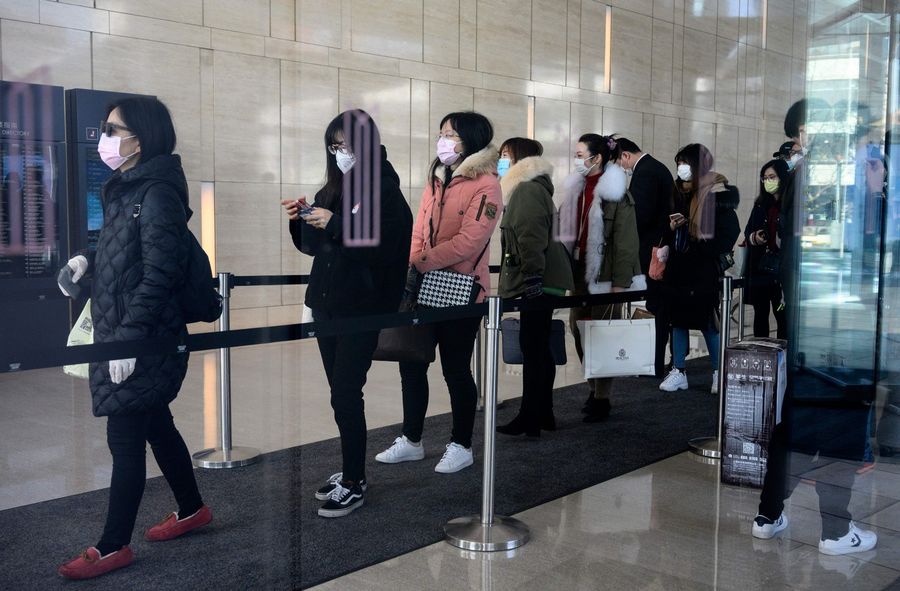 Employees wearing protective face masks queue as they return to work at an office building in Shanghai on 10 February 2020. (Noel Celis/AFP)