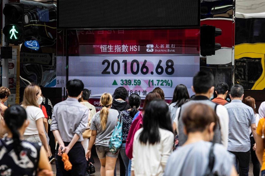 People walk past an electronic display of the Hang Seng Index in Hong Kong, China, on 4 August 2022. (Isaac Lawrence/AFP)