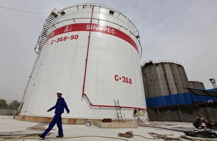 An employee walks past oil tanks at a Sinopec refinery in Wuhan, Hubei province, in this 25 April 2012 file photo. (Reuters)