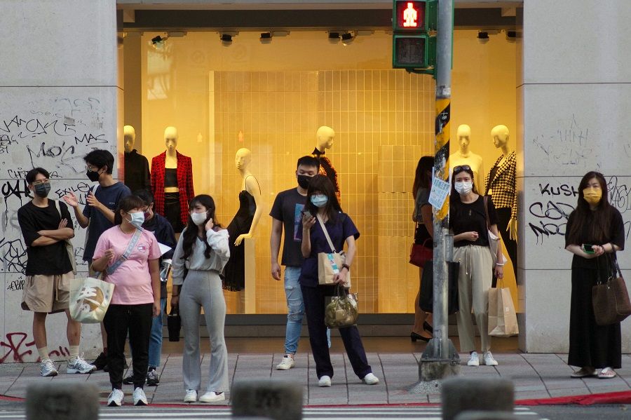 People wait to cross the road in front of a clothes shop along Zhongxiao East Road, in Taipei, Taiwan, on 29 September 2022. (Photo by Sam Yeh/AFP)