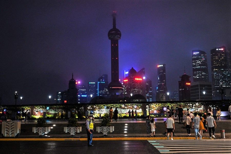 People cross a street in Shanghai, China, on 23 August 2022. (Hector Retamal/AFP)