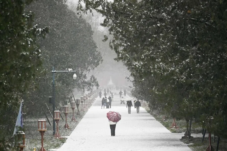 People walk along a road covered in snow in Beijing, China on 12 December 2025. (Wang Zhao/AFP)