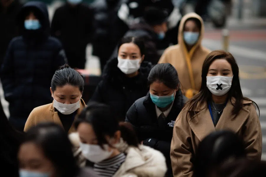 People wearing protective face masks cross a street in Beijing, China, 29 November 2021. (Thomas Peter/Reuters)