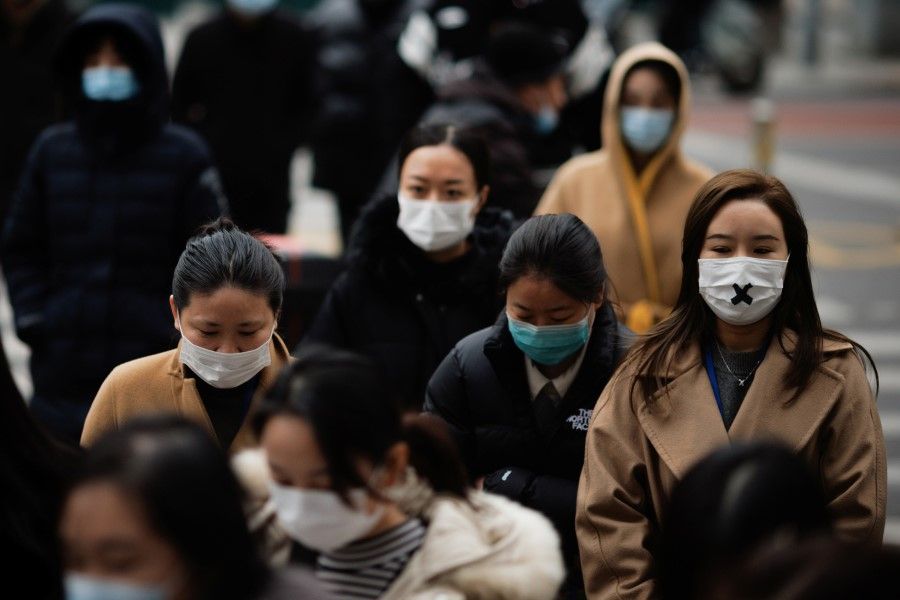 People wearing protective face masks cross a street in Beijing, China, 29 November 2021. (Thomas Peter/Reuters)