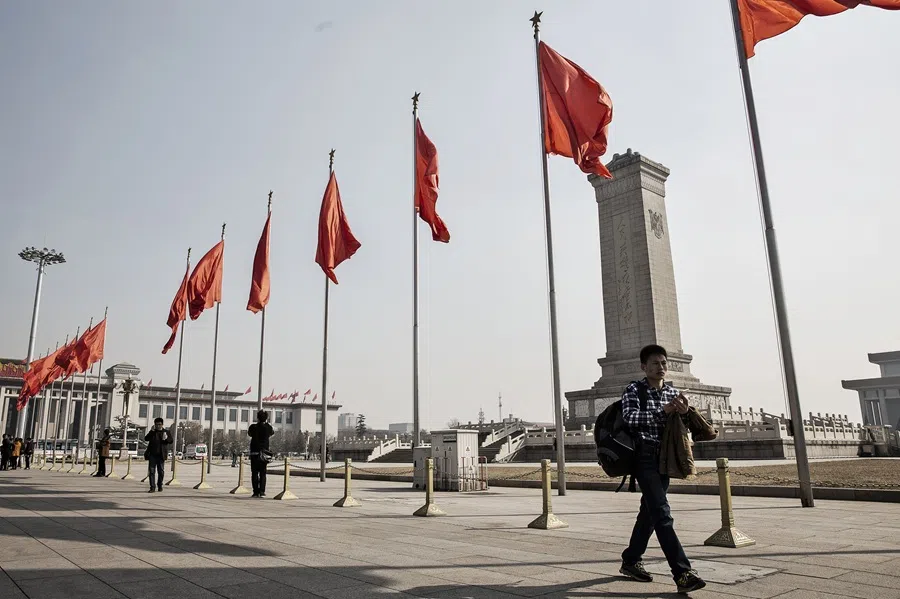 Pedestrians walk past red flags at Tiananmen Square in Beijing, China, on 2 March 2016. 