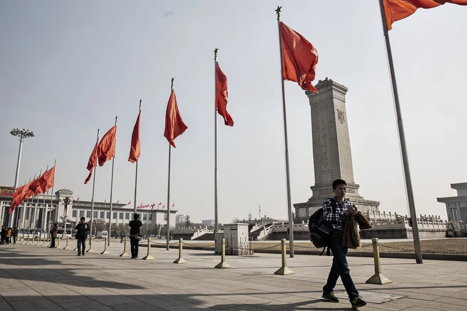 Pedestrians walk past red flags at Tiananmen Square in Beijing, China, on 2 March 2016.  (Qilai Shen/Bloomberg)