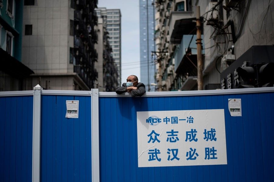 A man wearing a face mask looks over a barricade set up to keep people out of a residential compound in Wuhan in China's central Hubei province on April 14, 2020. (Noel Celis/AFP)