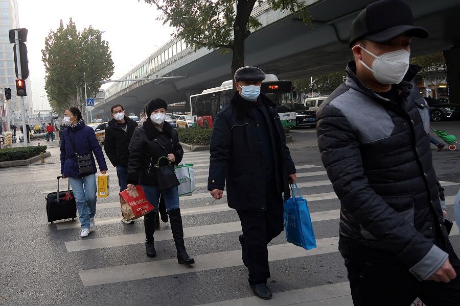 People cross a road amid the Covid-19 outbreak, in Wuhan, Hubei province, China, 31 December 2022. (Tingshu Wang/Reuters)
