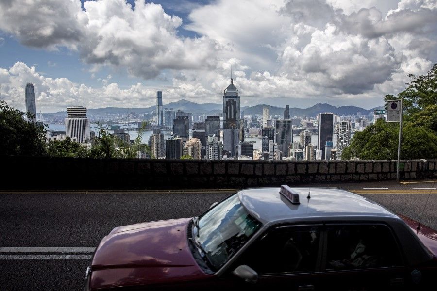 A taxi drives along a road before the city skyline in Hong Kong on 15 August 2020. (Isaac Lawrence/AFP)