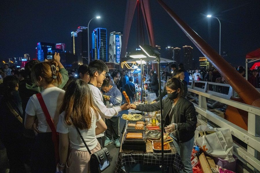 Customers buy food from street stalls in Chongqing, China, on 2 May 2024. (Raul Ariano/Bloomberg)