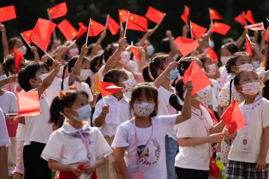 Students wave national flags during the first day of the new semester in Wuhan in China's central Hubei province on 1 September 2021. (STR/AFP)