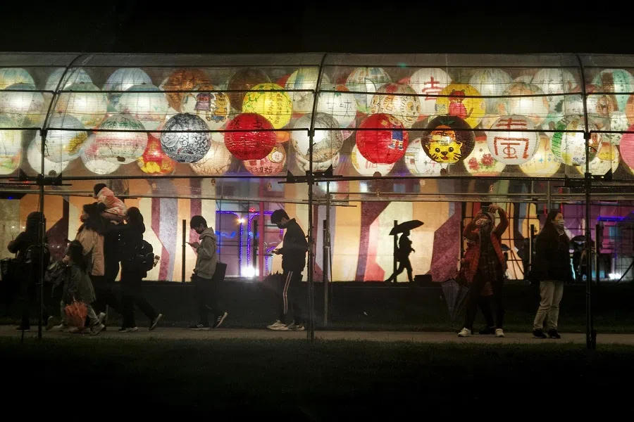 People walk under a row of lanterns on display in New Taipei City, Taiwan, on 4 February 2022. (Sam Yeh/AFP)