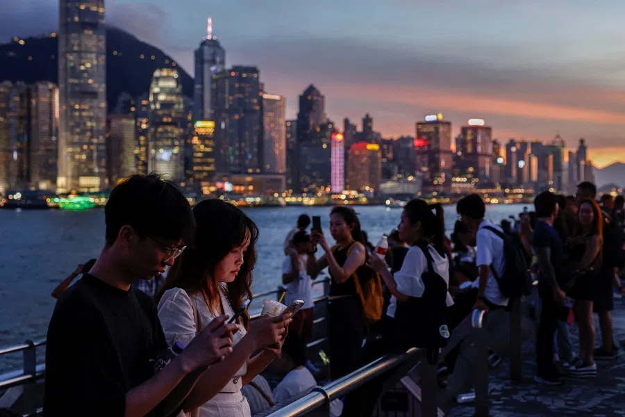 Tourists rest by the waterfront in Tsim Sha Tsui, with Hong Kong’s financial district visible in the background in Hong Kong, China, on 23 July 2024.