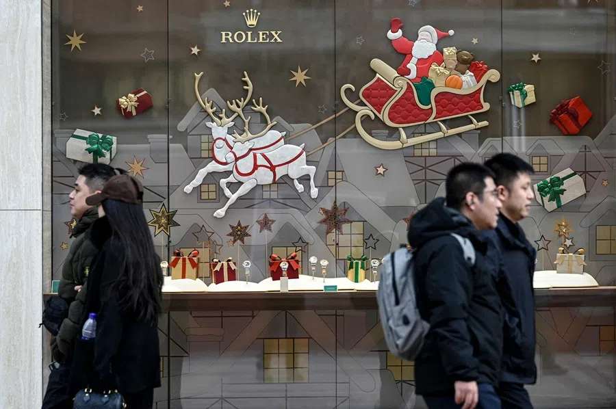 People walk past Christmas decoration outside a store of Swiss luxury watchmaker Rolex along a shopping street in Beijing on 15 December 2025. (Wang Zhao/AFP)