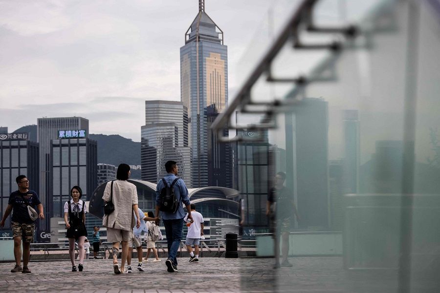 People walk along a promenade next to Victoria Harbour in Hong Kong, China, on 31 August 2023. (Isaac Lawrence/AFP)